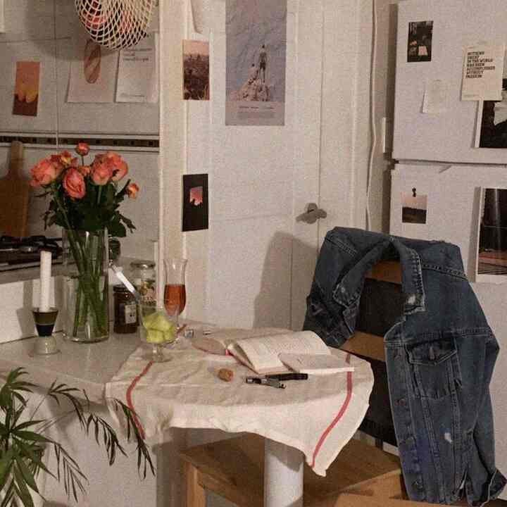 Warm gray and white toned kitchen space featuring a small round dining table, denim jacket, and roses in a vintage style interior
