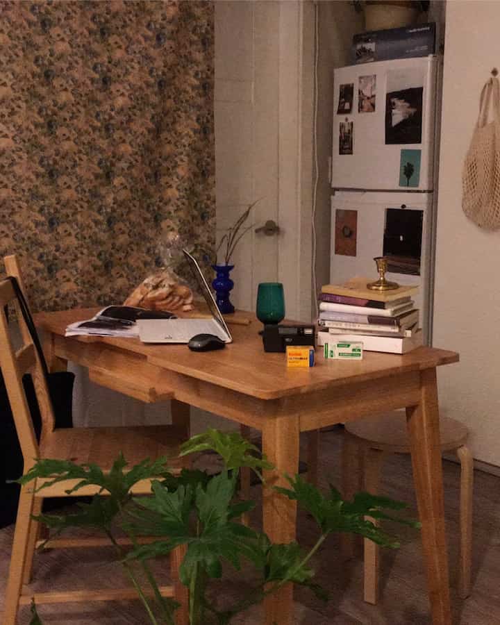 温かみのあるブラウンのナチュラルカラーの一人暮らし用作業兼食事スペース、木製ダイニングテーブルとファブリックカーテンが調和した雰囲気のあるインテリア