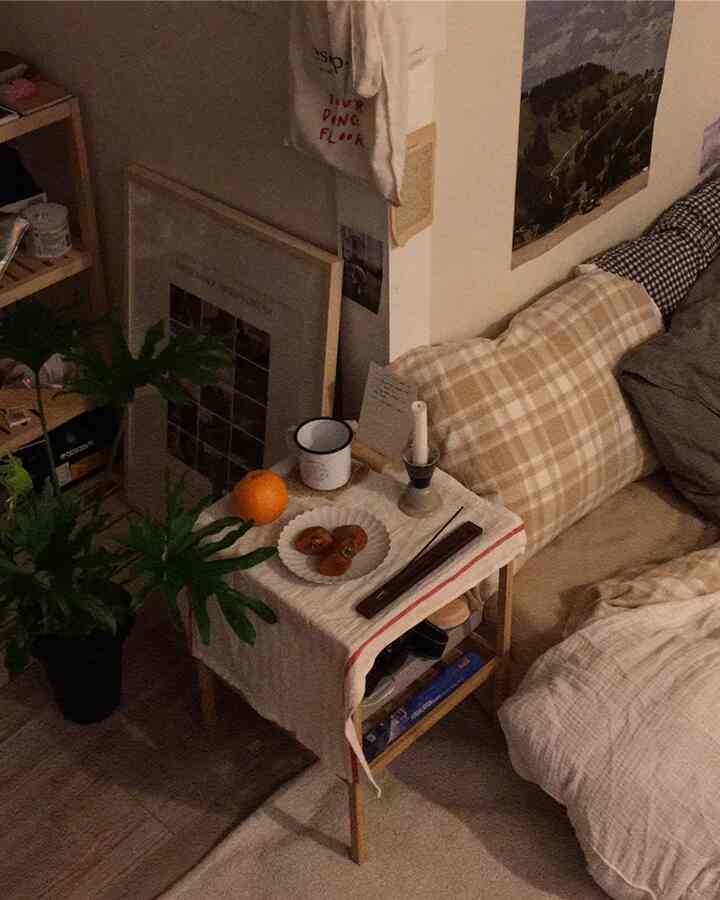 Natural-toned bedroom featuring beige bedding and wooden nightstand with plants creating a cozy atmosphere
