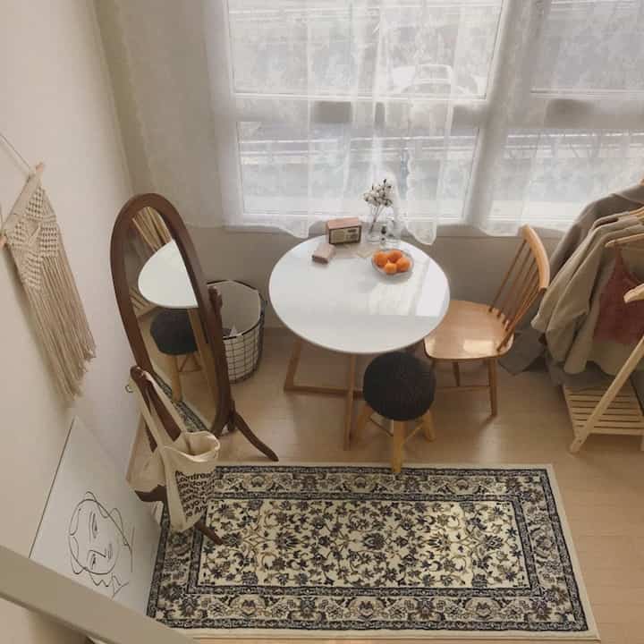 Natural-toned studio dining room featuring wooden furniture and patterned rug in a cozy home cafe setting