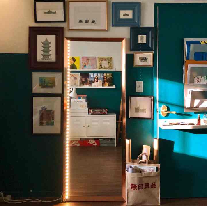 Green and white toned walk-in closet space featuring a central full-length mirror and framed wall art with a cozy atmosphere
