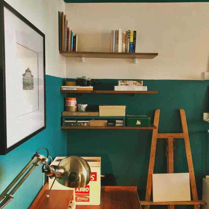 Small room with brown wood tones and blue walls, shelves and desk with reading lamp create a cozy study space