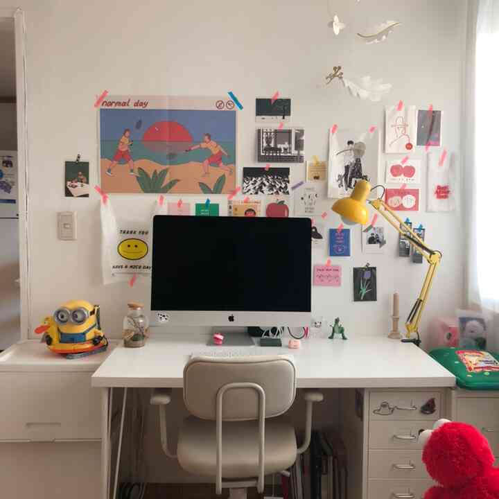 White and yellow toned studio workspace featuring a desk with computer and ergonomic chair, creating a clean and cozy interior