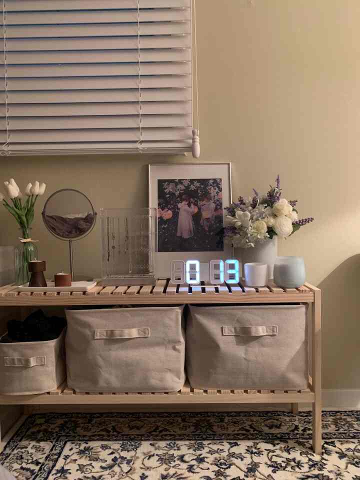 Natural tone bedroom featuring wooden storage rack with fabric baskets and poster, creating a cozy and organized interior