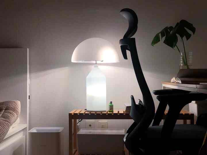 Soft white and wood-toned bedroom space featuring a floor lamp and office chair, creating a home office atmosphere