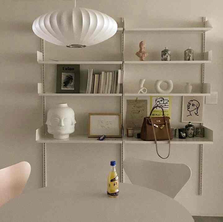 ホワイトトーンのリビングルーム、中央に大きな棚と丸いテーブルが配置されたシンプルで北欧風のインテリア