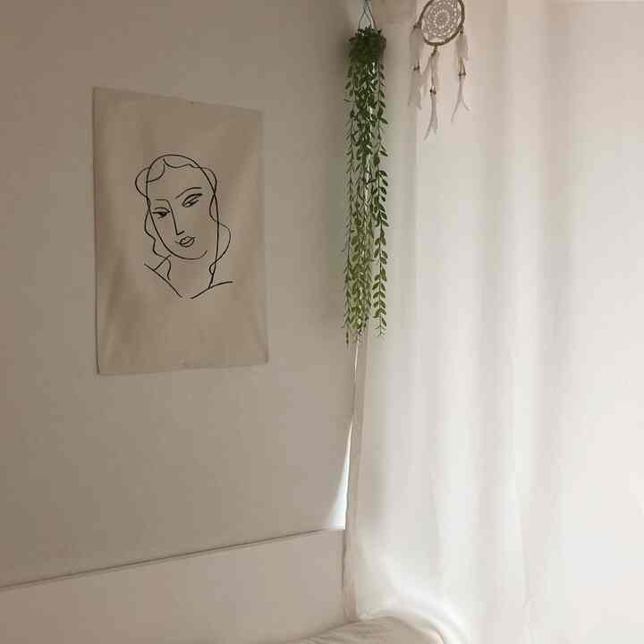 Cozy studio bedroom with soft white curtains and natural green artificial plant accent, featuring simple and emotional décor