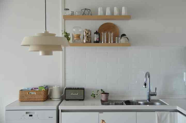 白と木目調が調和したキッチン空間、棚とペンダントライトが配置された清潔感のあるカフェ風インテリア
