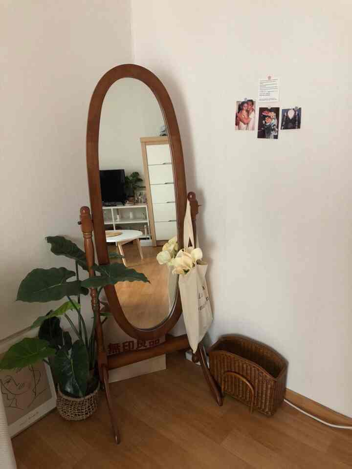 ナチュラルな木目調と植物が調和した小さな空間、木製の全身鏡とシンプルなオブジェが配置された温かみのある部屋