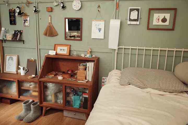 ナチュラルなブラウン色調の寝室、木製のチェストとパターンの枕が配置された温かみのある空間