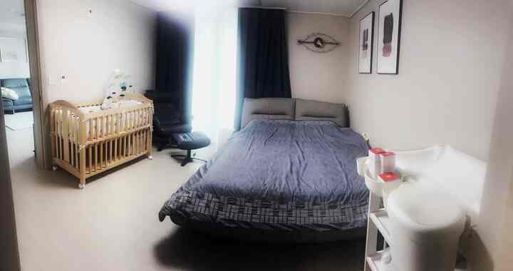 ネイビーとホワイトの色調の寝室、ベビーベッドとリクライナー、オムツ交換台が配置されたモダンな主寝室のインテリア