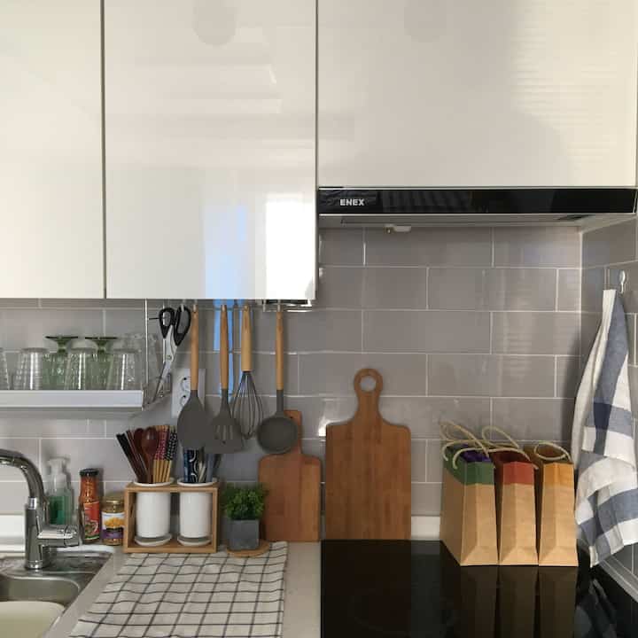 Clean kitchen with white cabinets and wood tones, featuring organized kitchen utensils and cutting boards in a minimalist setting