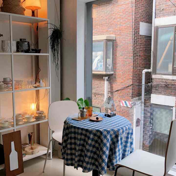 A white and blue toned dining room featuring a vintage checkered tablecloth and plants, creating a cozy home cafe atmosphere