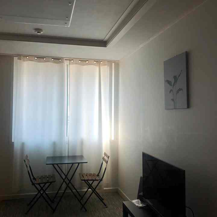 White-toned walls and curtains with black folding dining table and chairs in a cozy small living space for two