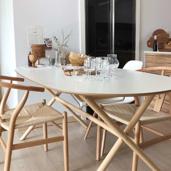 Bright kitchen dining space blending wood tone and white, featuring rattan decor and clear glassware for a natural home cafe atmosphere