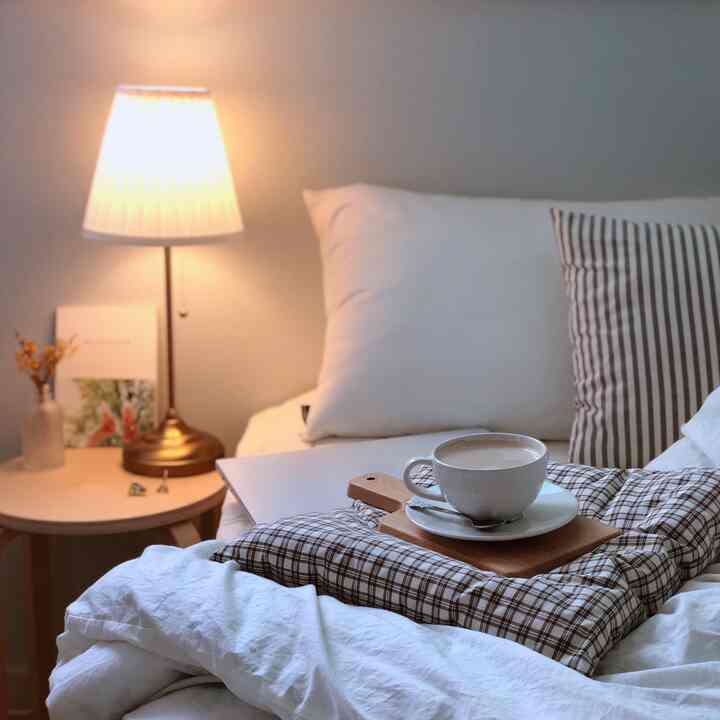 Warm beige and white toned bedroom featuring checkered cushions and a coffee cup creating a cozy atmosphere