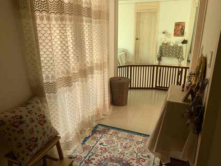 Beige-toned living room entrance featuring floral curtains, a patterned rug, and a wooden pet gate creating a cozy atmosphere