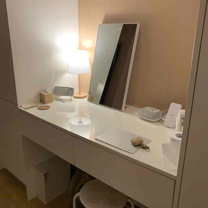 A compact powder room in white and beige tones featuring a clean vanity, mirror, and table lamp in a simple modern setting