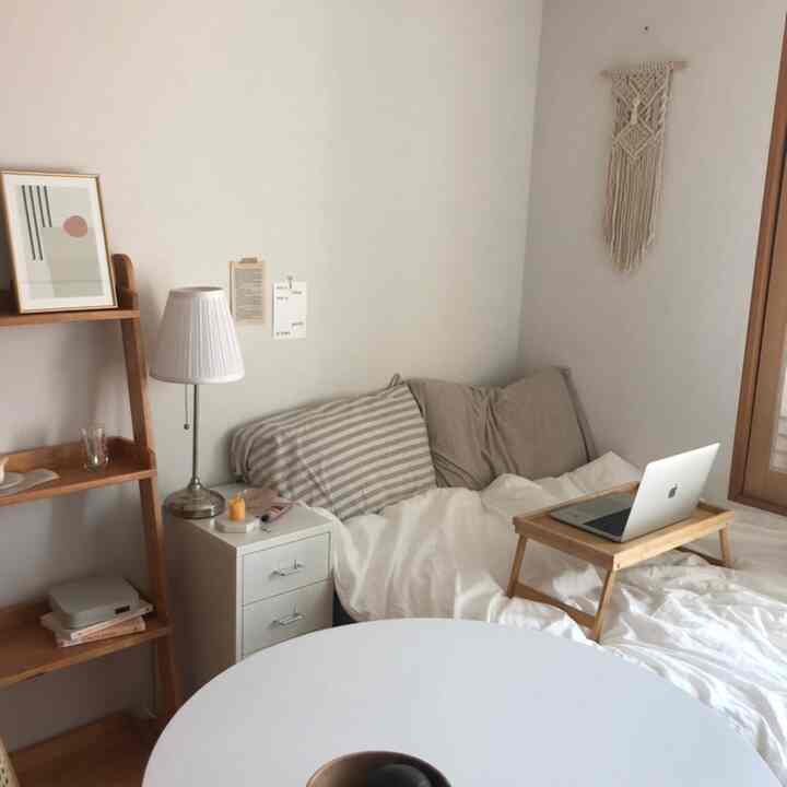 Natural bedroom in white and wood tones featuring a bed, wooden shelf, and macrame decor in a cozy atmosphere