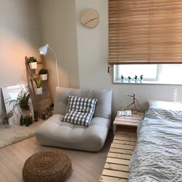 A natural wood tone and white studio bedroom featuring a cozy sofa and wooden bed, creating a warm and inviting space