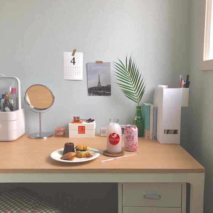 Natural-toned home office space with soft light blue walls and wooden desk featuring organized items and small decor