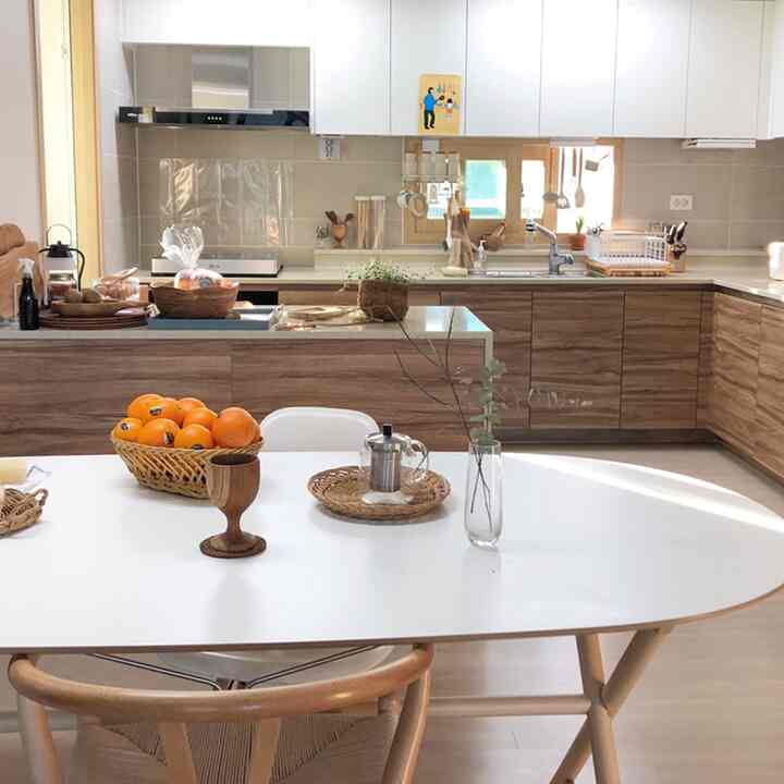 A white and wood tone kitchen and dining table featuring rattan accessories that add a natural atmosphere