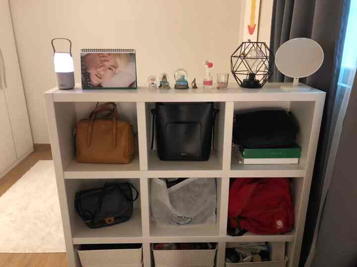 ホワイトとナチュラルトーンの正方形の部屋、本棚にバッグや雑貨を収納した印象的な空間