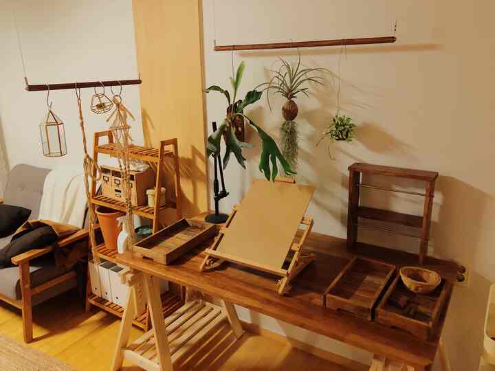 Natural-toned living workspace with warm brown wooden table and hanging plants against a white wall