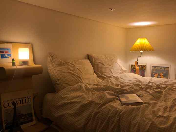 Warm beige loft bedroom featuring checked bedding and yellow table lamp, creating a cozy atmosphere