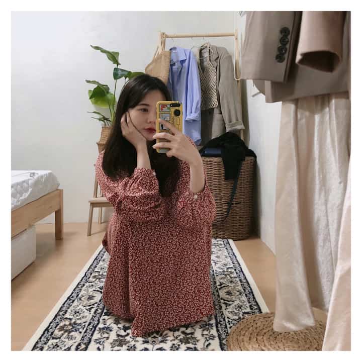 Natural beige toned bedroom featuring wooden bed, clothes rack, patterned rug, and a large full-length mirror creating cozy atmosphere