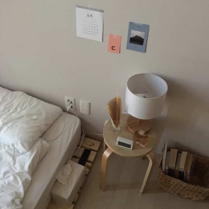 White and wood-tone bedroom featuring wooden stool and lamp with simple, cozy atmosphere
