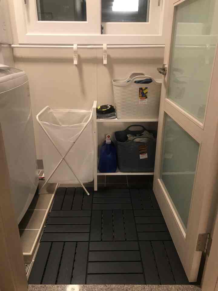 White and dark gray toned small laundry room featuring IKEA shelves and organized laundry baskets with a practical layout