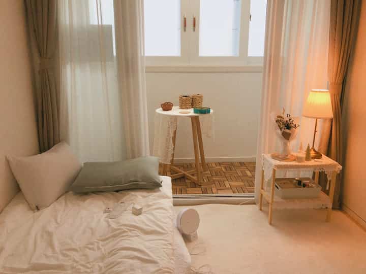 White and wood tone bedroom and veranda featuring rug, curtains, and warm lighting creating a cozy atmosphere