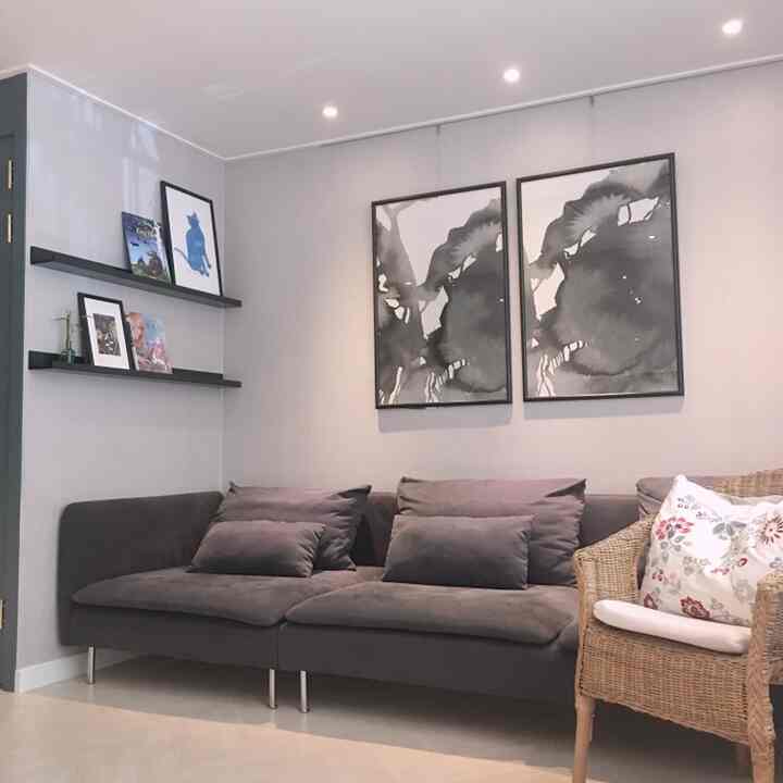 Calm gray-tone living room featuring a gray fabric sofa, rattan armchair, and black-and-white wall art creating a stylish atmosphere