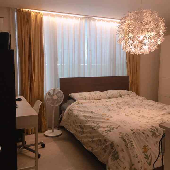 Bright white and brown toned bedroom featuring floral bedding, blackout curtains, bed and desk creating a cozy atmosphere