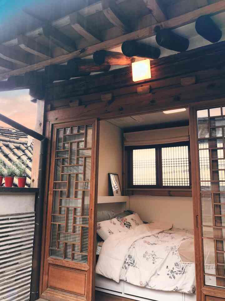 Cozy bedroom with warm wood tones and traditional Hanok-style windows, featuring floral bedding for a soft atmosphere
