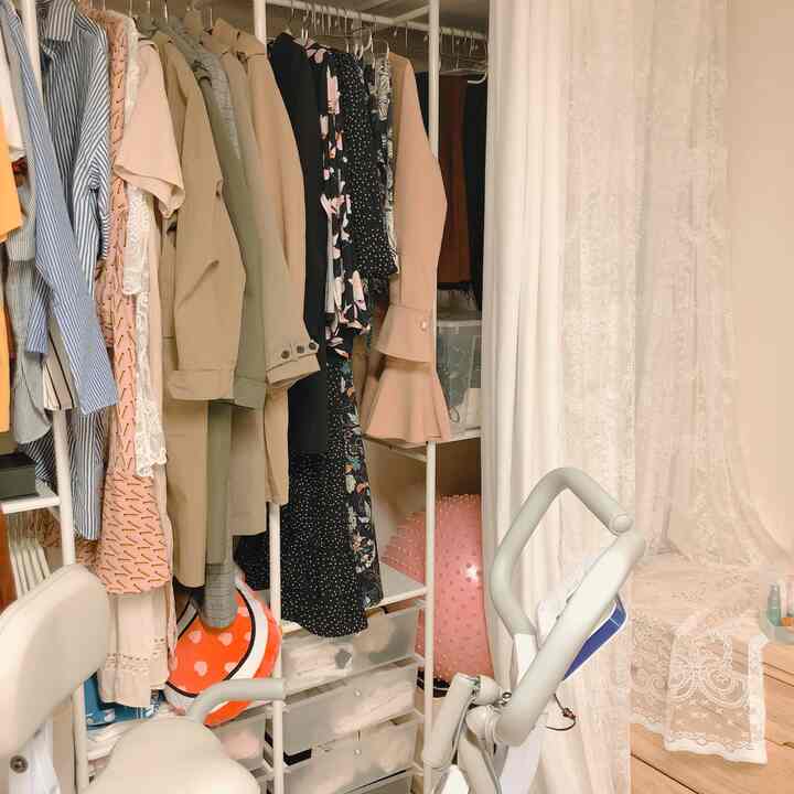 白とベージュの色調のウォークインクローゼット、ハンガーラックと二重カーテンが配され、落ち着いた印象のインテリア