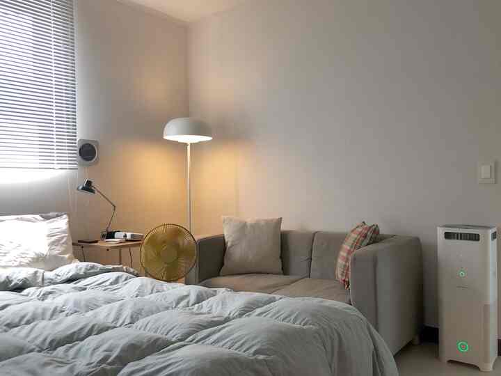 Beige and white toned bedroom featuring sofa and various lighting fixtures in a cozy setting