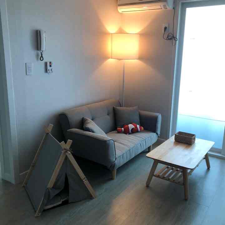 Compact and clean living room with white walls, gray sofa bed, and wood-tone coffee table