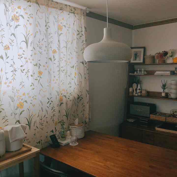 Natural wood-tone dining room featuring floral curtains and a pendant light above the table