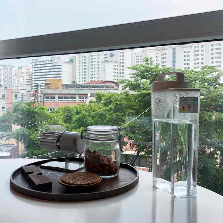 透明なガラス容器と木目調のトレイが窓辺に置かれたシンプルなキッチンの雰囲気あるインテリア