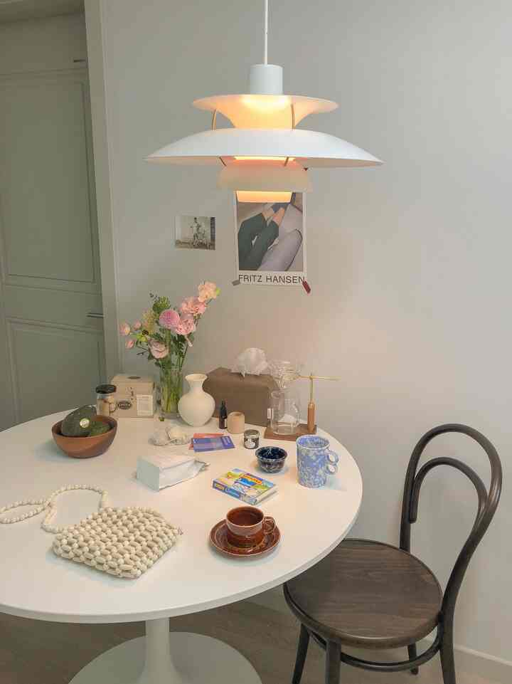 Bright white and dark brown toned round dining table with drip coffee equipment and vase, creating a cozy home cafe space