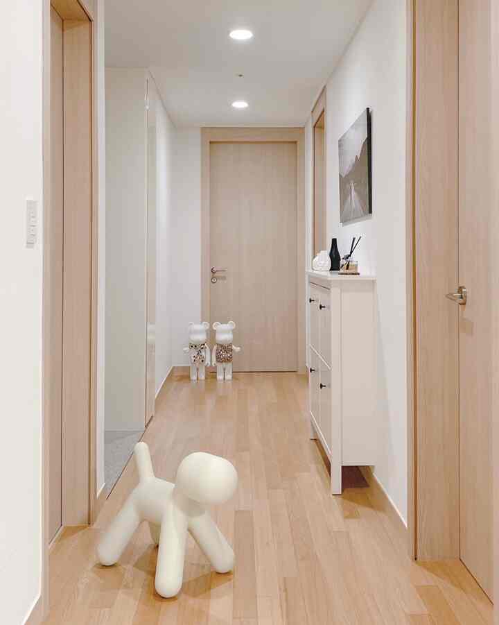 白い壁と木目調の床、靴箱が配置されたシンプルな廊下のインテリア