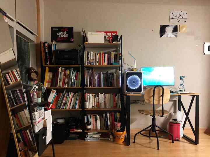 Wood and black tone studio study corner featuring bookshelves, desk, and chair in a cozy arrangement