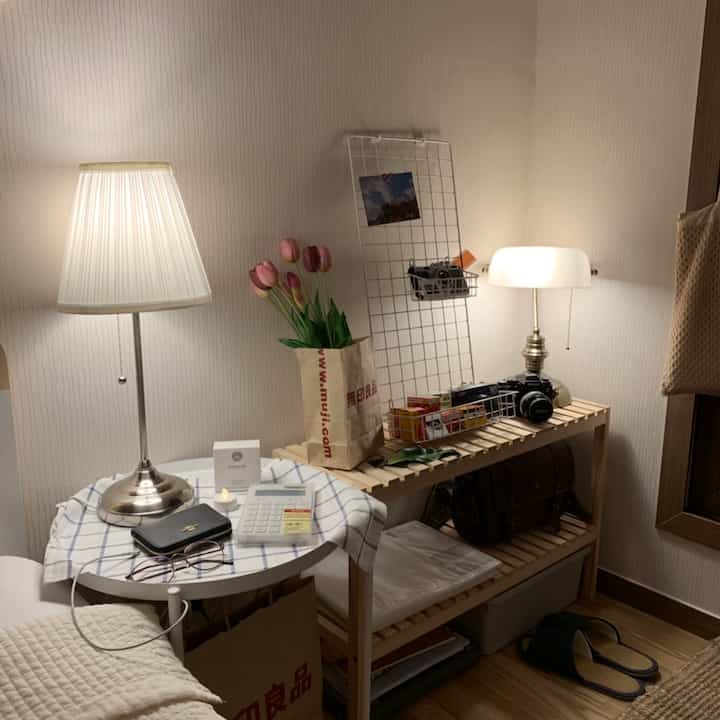 ナチュラルカラーの小さな部屋、木製の棚と白いランプが配置された雰囲気のあるインテリア