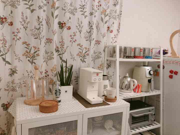 White and natural tone kitchen space featuring a coffee machine, shelves, and cabinet arranged neatly in a home cafe setup