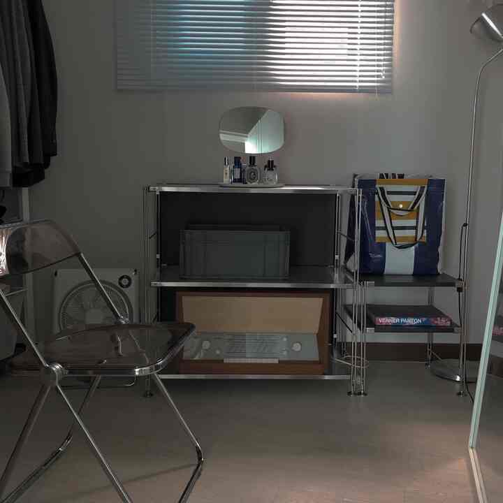 A minimal entrance space in white and gray tones featuring metal shelves and blinds with storage ideas
