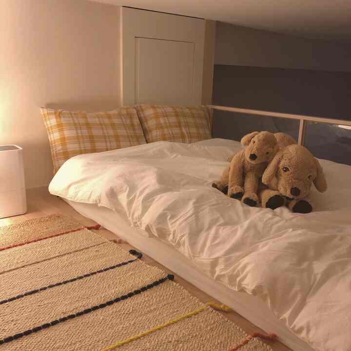 Cozy bedroom with white bed and beige rug under warm ambient lighting