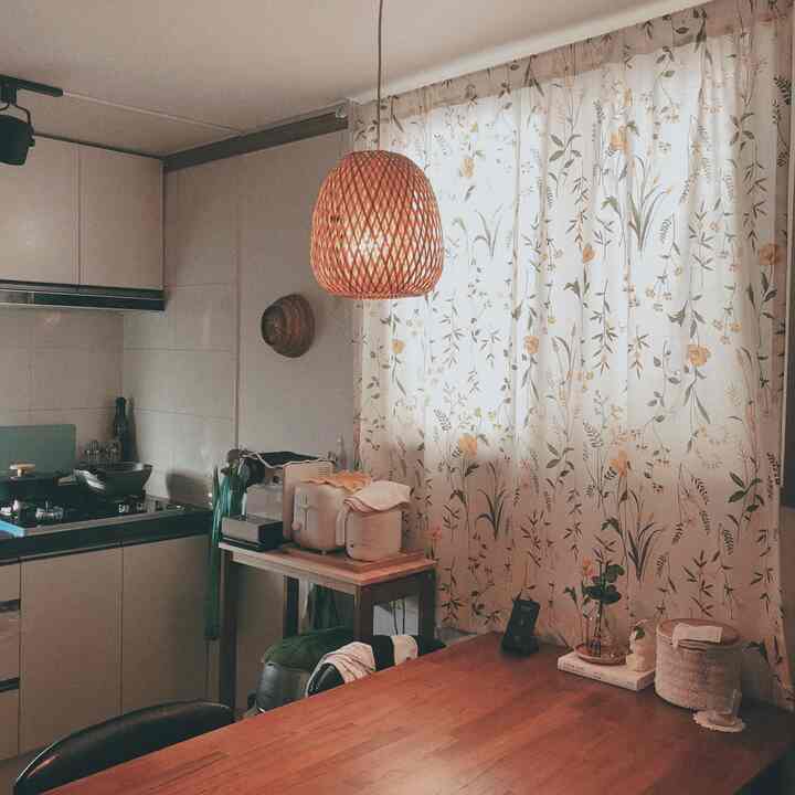 Natural toned vintage kitchen space featuring a rattan pendant light and floral curtains creating a cozy atmosphere
