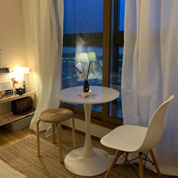 ナチュラルな色調のワンルーム、丸テーブルとスツールが配置された温かみのある空間